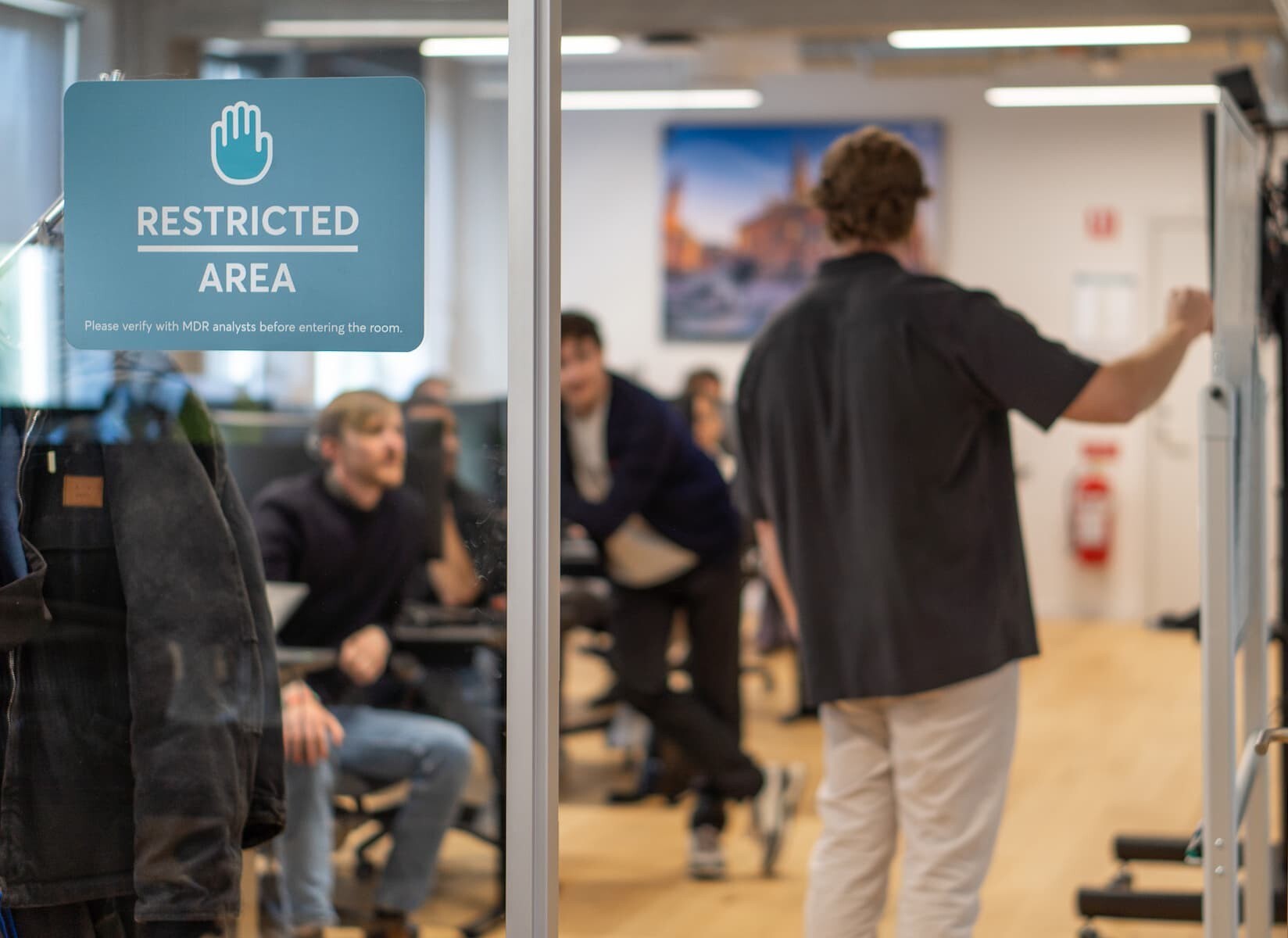 Man writing on whiteboard in front of his team of colleagues