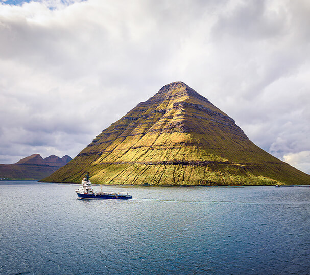 Ship sails along the island of Kunoy in the Faroe Islands