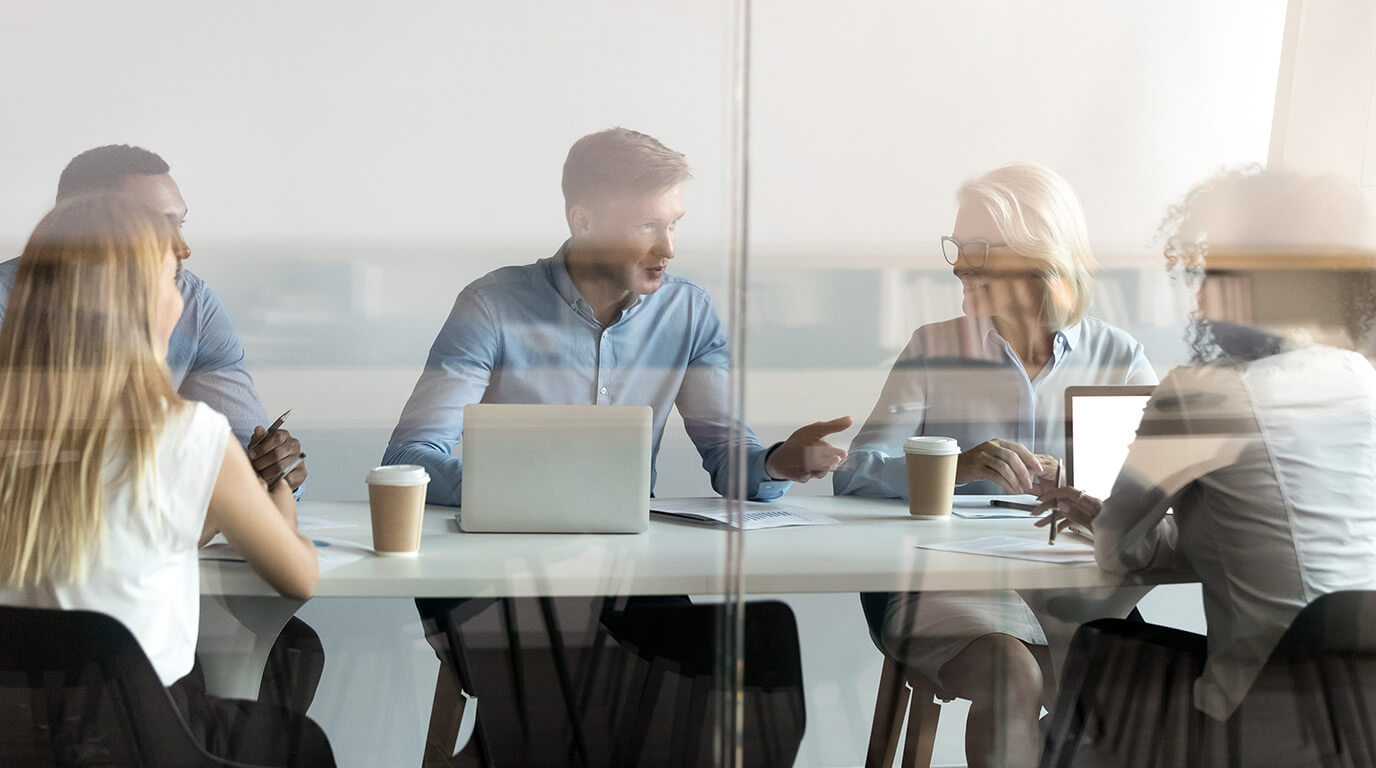 Team meeting around a table with laptops